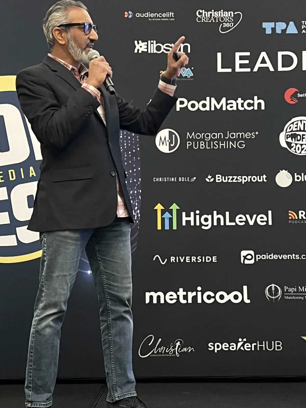 Junaid Ahmed speaking on stage at Podfest 2026